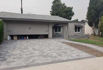 Exterior view of white sectional garage door and driveway at North Salt Lake home before repair service.