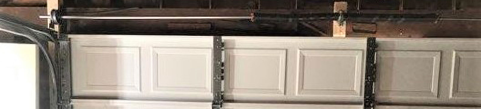 Interior of Clinton, UT garage showing freshly installed white sectional garage door and secure steel tracks.